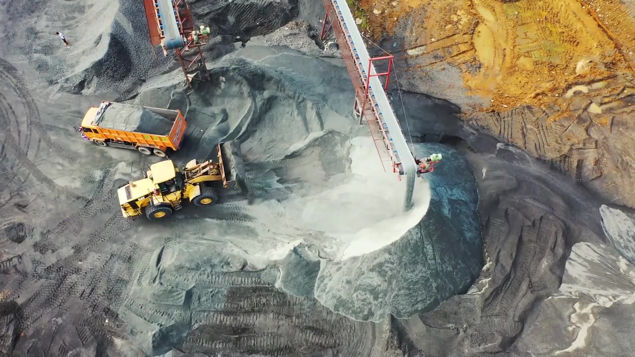 Radlader belädt im Kieswerk unter dem Förderband